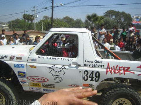 1990 Ford Bronco - Side view of a white off-road race truck #349 lettered Ken Casper Leavitt with crew chief Ray Leavitt and red Anger graphics.