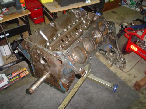 1976 Ford F-100 - An engine block sits on a stand in a garage, with tools and equipment in the background.