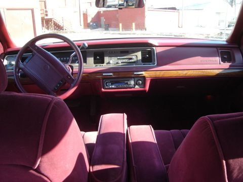 1992 Ford Crown Victoria - The interior of a 1992 Ford Crown Victoria features maroon velour upholstery, wood grain accents, and a classic dashboard layout.