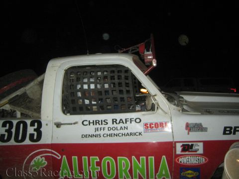 1990 Ford Bronco - Close view of white race truck number 303 showing its window net and lettering for Chris Raffo, Jeff Dolan and Dennis Chencharick.