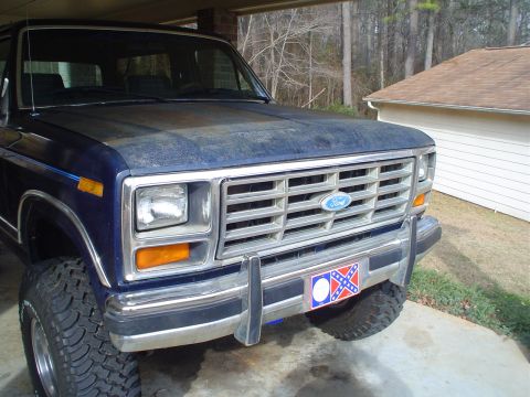 1984 Ford Bronco - Front view of a blue Ford Bronco, likely from the early 1980s, parked under a carport.