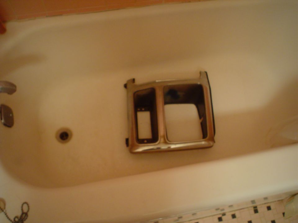 Chrome headlight bezel with dual openings, sitting in a bathtub