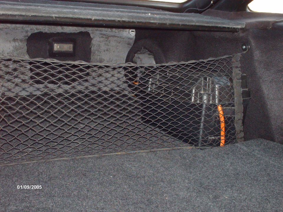 Trunk cargo net with a black storage box and orange handle visible behind it