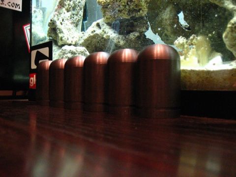 1989 Ford Bronco - Several metallic cylindrical objects are lined up on a wooden surface in front of a large aquarium display.