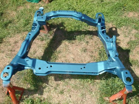 1992 Ford Taurus - A teal painted subframe rests on orange jack stands on a grassy area.