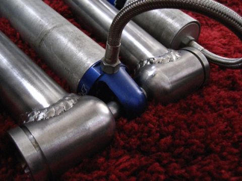 1989 Ford Bronco - Multiple shock absorbers are shown in detail, with visible welding and braided lines against a textured red background.