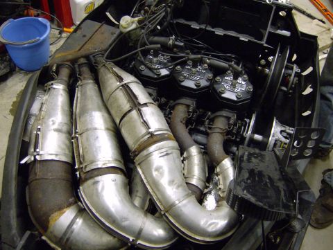 1982 Chevrolet C/K Pickup - The engine compartment of a snowmobile, showing the triple exhaust pipes and the engine block with three cylinders.