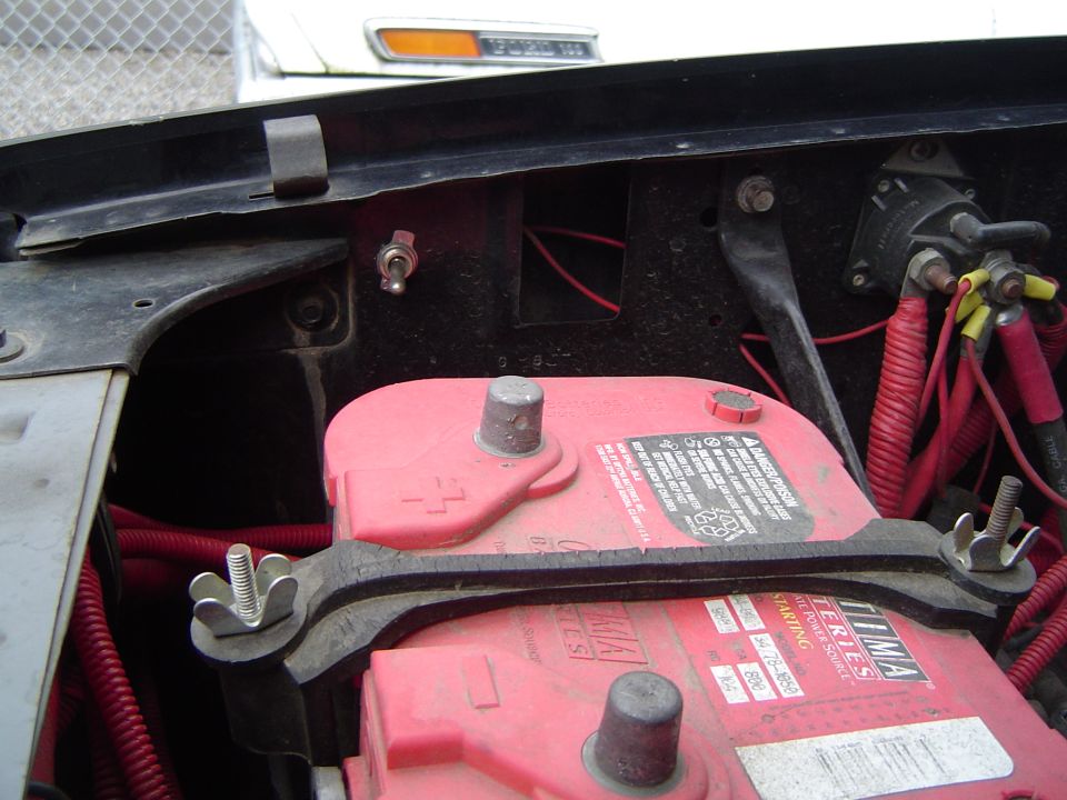 Close-up of two red car batteries with wiring and a toggle switch