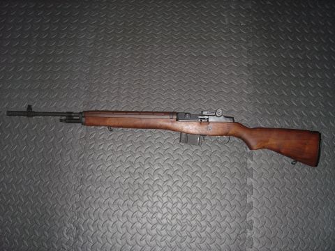 1990 Ford Bronco - A rifle with a wooden stock and metal barrel is displayed against a textured surface.