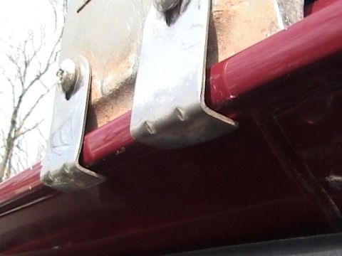 1990 Ford Bronco - Close-up of metal brackets attached to the side of a red vehicle.