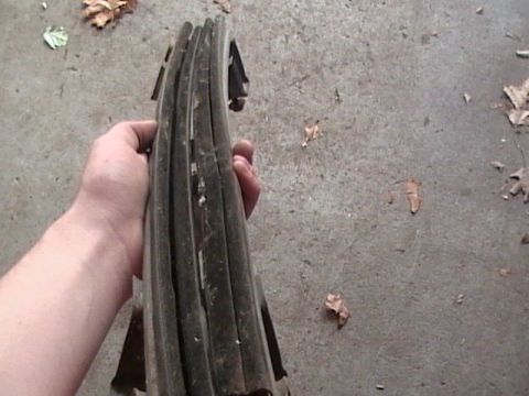 1990 Ford Bronco - A hand holds a stack of weathered car door seals against a concrete background with scattered leaves.