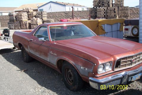 1973 Ford Ranchero - This 1973 Ford Ranchero Squire shows signs of wear and tear, parked in a lot with stacked materials.