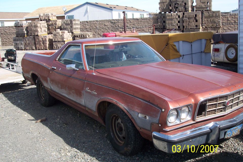 Red 1973 Ford Ranchero Squire with faded paint and chrome bumper, parked outdoors