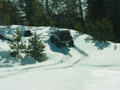 1986 Ford Bronco - A truck navigates a snow-covered slope, leaving tire tracks behind.