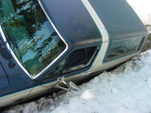 1986 Ford Bronco - This 1986 Ford Bronco is partially buried in snow, showing its distinctive two-tone paint and roof stripe.