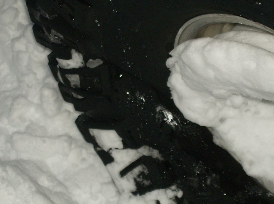 Close-up of a black tire partially covered in snow