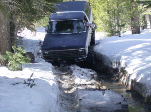 1986 Ford Bronco - Ford Bronco navigates a challenging snowy path with water runoff.