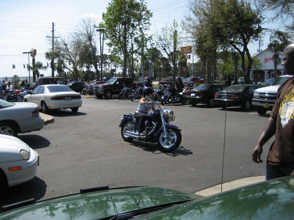 guy on a blue motorcycle in a parking lot, cars and other bikes around