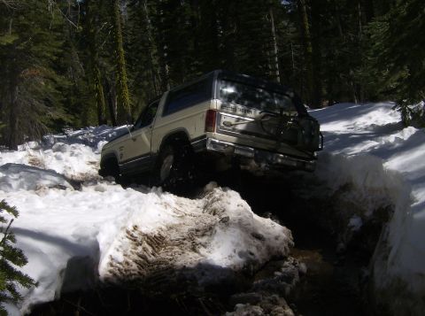 1986 Ford Bronco - This 1986 Ford Bronco is shown off-roading through a snowy path in a wooded area.