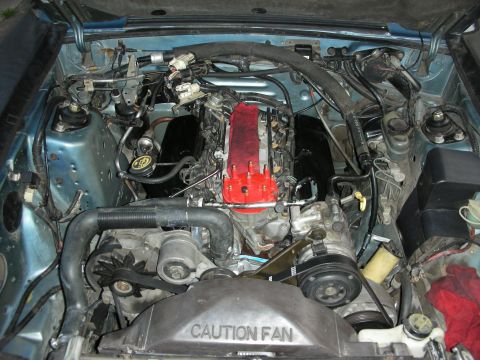 1990 Ford Mustang - The engine bay of a car is shown, with various components and wiring visible. A caution fan warning is present.