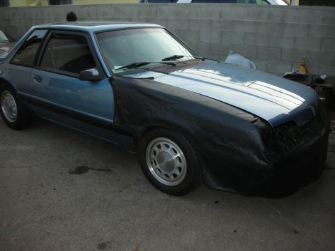 1990 Ford Mustang - Blue 1990 Ford Mustang coupe with a black cover on the front fender and bumper.