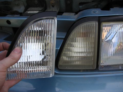 1990 Ford Mustang - A new headlight assembly is being compared to an older, yellowed one on a blue vehicle.