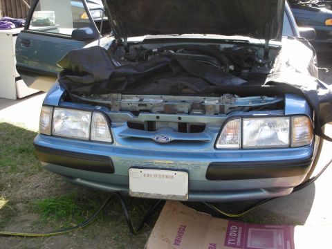 1990 Ford Mustang - Front view of a blue 1990 Ford Mustang with its hood open, revealing a tarp-covered engine bay.