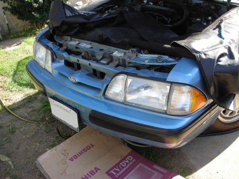 1990 Ford Mustang - The front end of a blue 1990 Ford Mustang is shown with the engine bay partially covered by a protective tarp.
