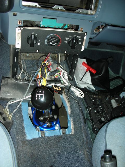 1990 Ford Mustang - Interior view of a 1990 Ford Mustang with the center console disassembled, revealing wiring and the manual transmission shifter.