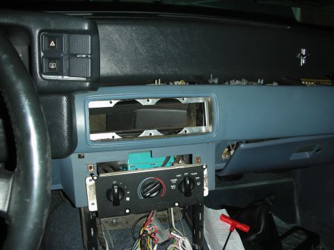 1990 Ford Mustang - Interior dash of an older vehicle with the radio removed, exposing the cavity above the climate control rotary knobs.