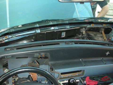 1990 Ford Mustang - Interior view of a teal vehicle with the dash pad and trim removed, exposing the firewall, steering column, and wiring.