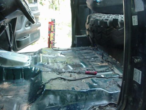1992 Ford Bronco - Interior of a truck with the carpet, seats and console stripped out, exposing the bare stamped floor pan with sealer beads, seat-mount hole…