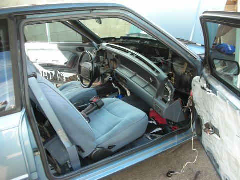 1990 Ford Mustang - The interior of a 1990 Ford Mustang shows extensive disassembly of the dashboard and door panels.