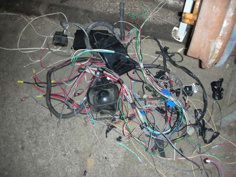 1990 Ford Mustang - A messy automotive wiring harness lies on the ground, a jumble of wires and connectors.