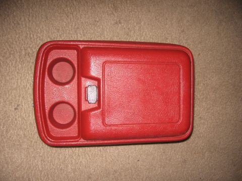 1990 Ford Bronco - Top-down view of a red plastic center console lid removed from the vehicle and laid on beige carpet, with two molded cup holders on the lef…