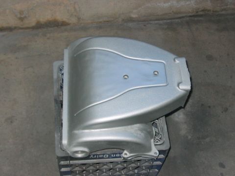 1991 Ford Bronco - A silver painted engine intake manifold part rests on a blue milk crate.
