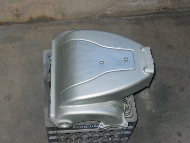 Silver painted engine intake manifold part on a blue milk crate