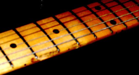 1975 Ford F-150 - Guitar neck detail with frets and strings visible against a dark background.