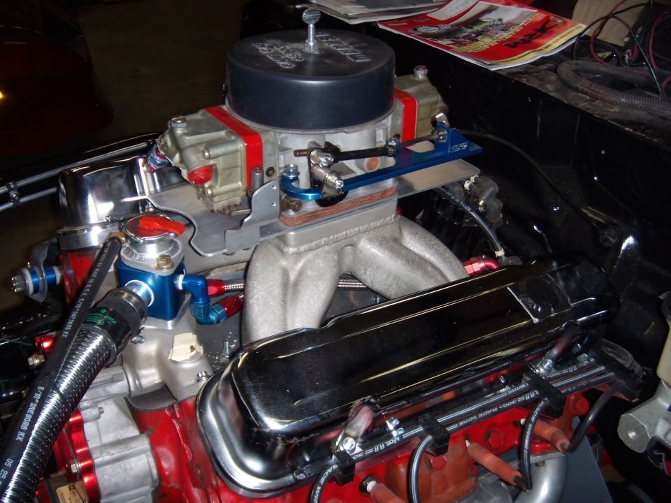 Close-up of a V8 engine showing a Holley carburetor, intake manifold, and valve covers