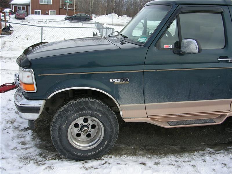 Front quarter of a green Ford Bronco on mud tires in snow