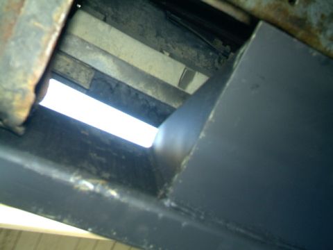 1989 Ford Bronco - Close-up view of the undercarriage of a vehicle, revealing structural components and a bright light source.