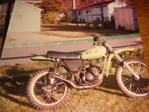 1996 Ford Bronco - A light green dirt bike with a black seat and knobby tires is parked on a grassy area in front of a building.