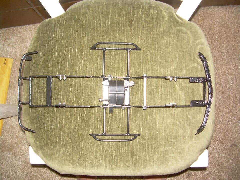 Metal frame, possibly for a model car or toy, resting on a green upholstered chair