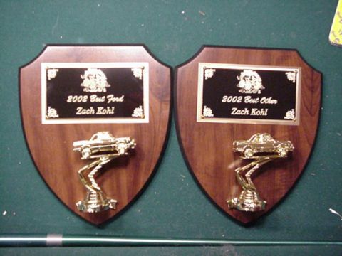 1992 Ford Bronco - Two shield-shaped wooden award plaques laid on green felt, each with a black engraved plate reading "2002 Best Ford: Zach Kohl" and "2002 B…