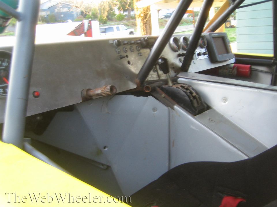 Interior cockpit of a tube-chassis race vehicle showing shifter and gauges