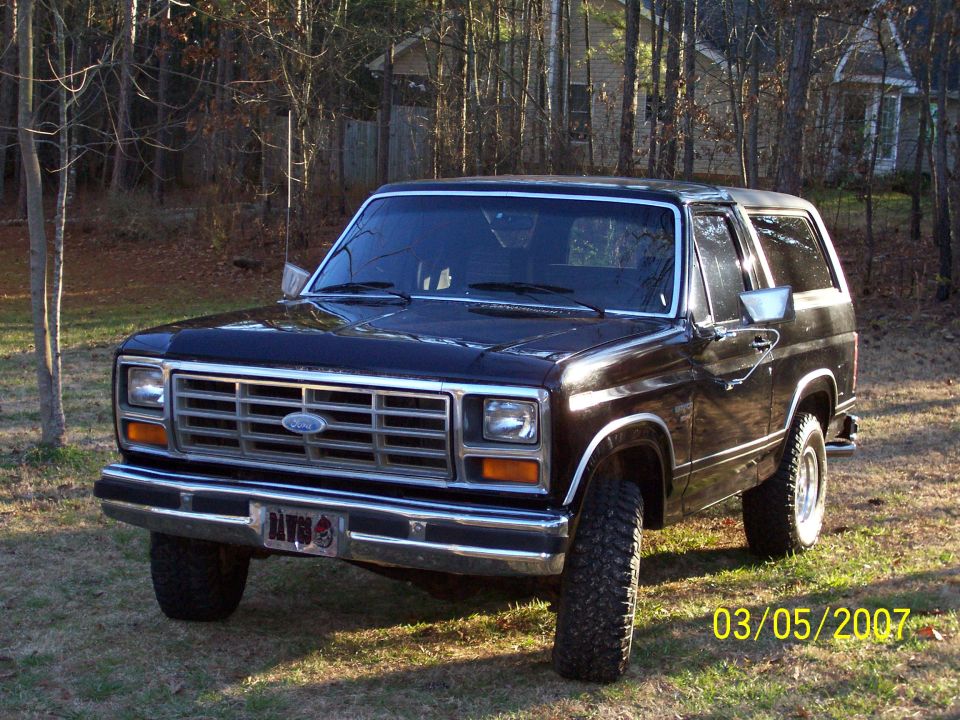 Black two-door Ford Bronco SUV, front 3/4 view, parked on grass