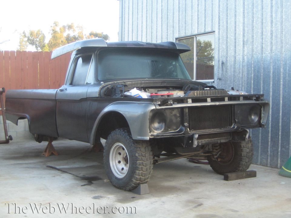 Vintage Ford truck project on jack stands with no front clip in a workshop