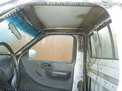 1990 Ford Bronco - Stripped interior of a Ford truck cab showing a bare door panel, side mirror, and exposed sheet metal during a build.