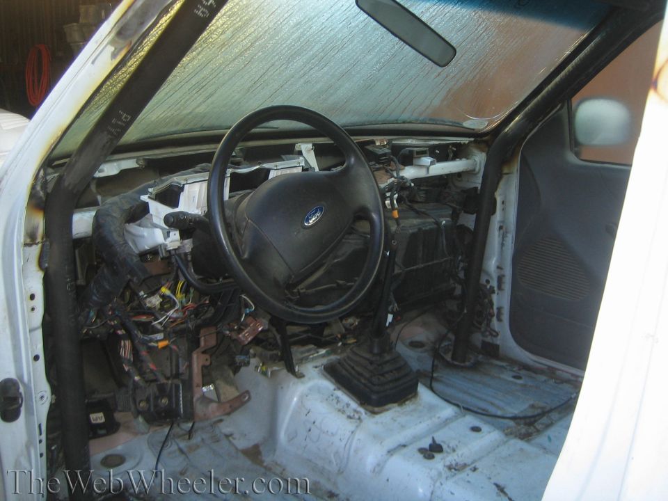 Gutted Ford truck interior with steering wheel and exposed dashboard wiring