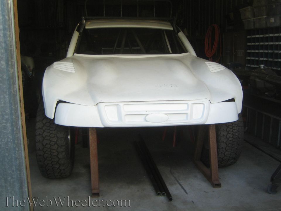 White fiberglass off-road truck body shell on stands in a shed